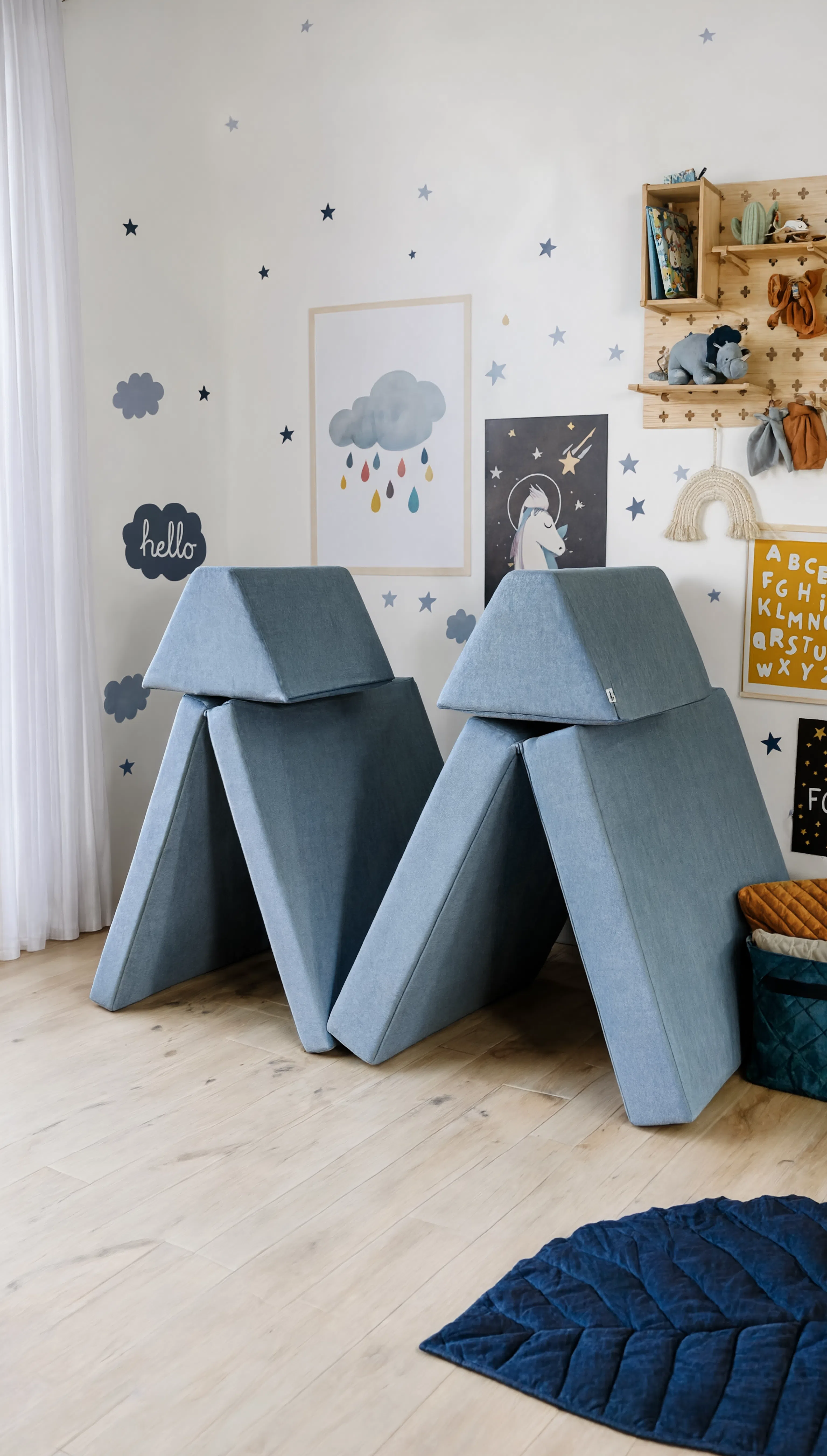 Two blue geometric chairs in a room with children's decor on the wall.