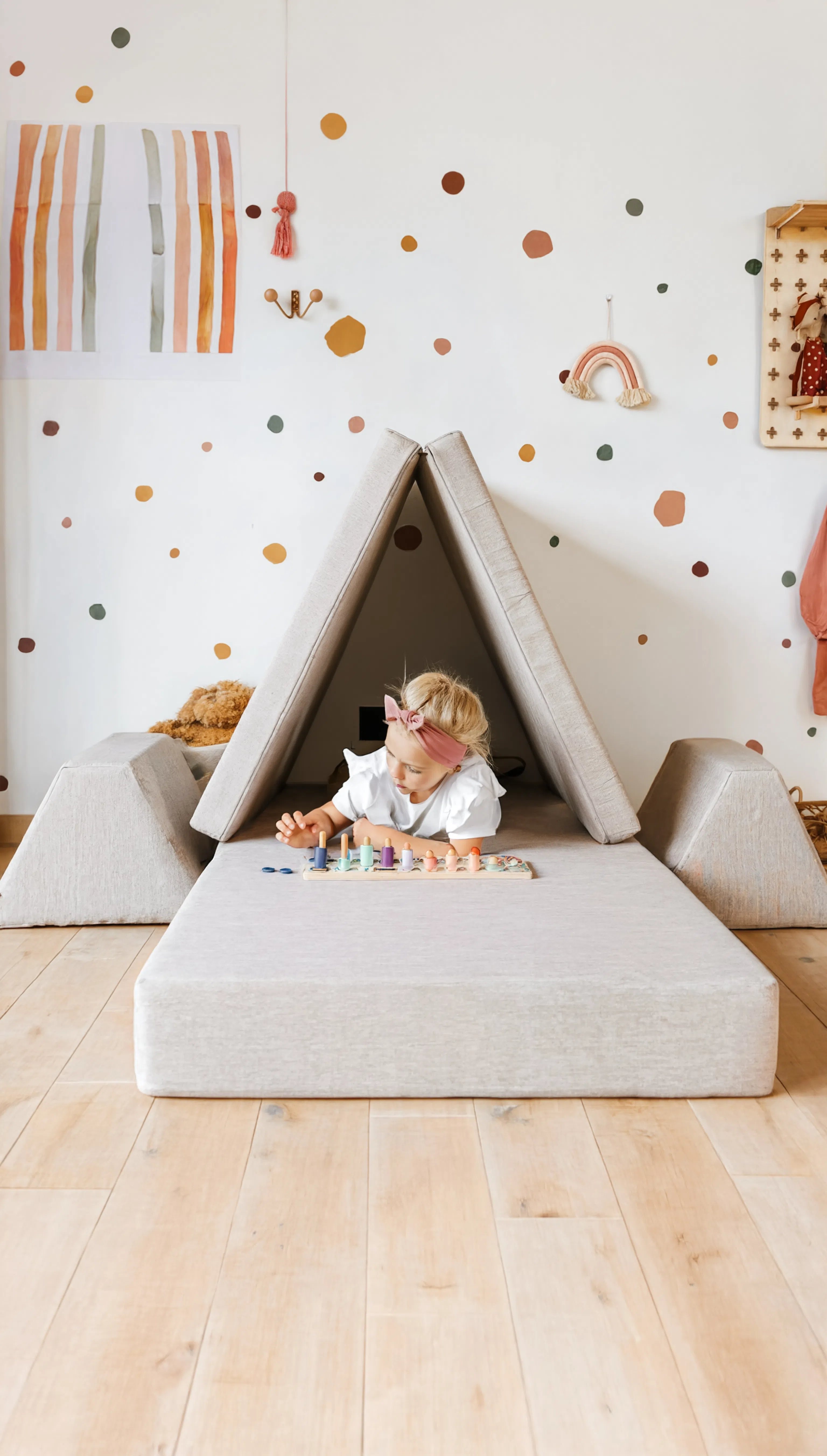 Child playing inside a small, white, cone-shaped playhouse with colorful wall decorations.
