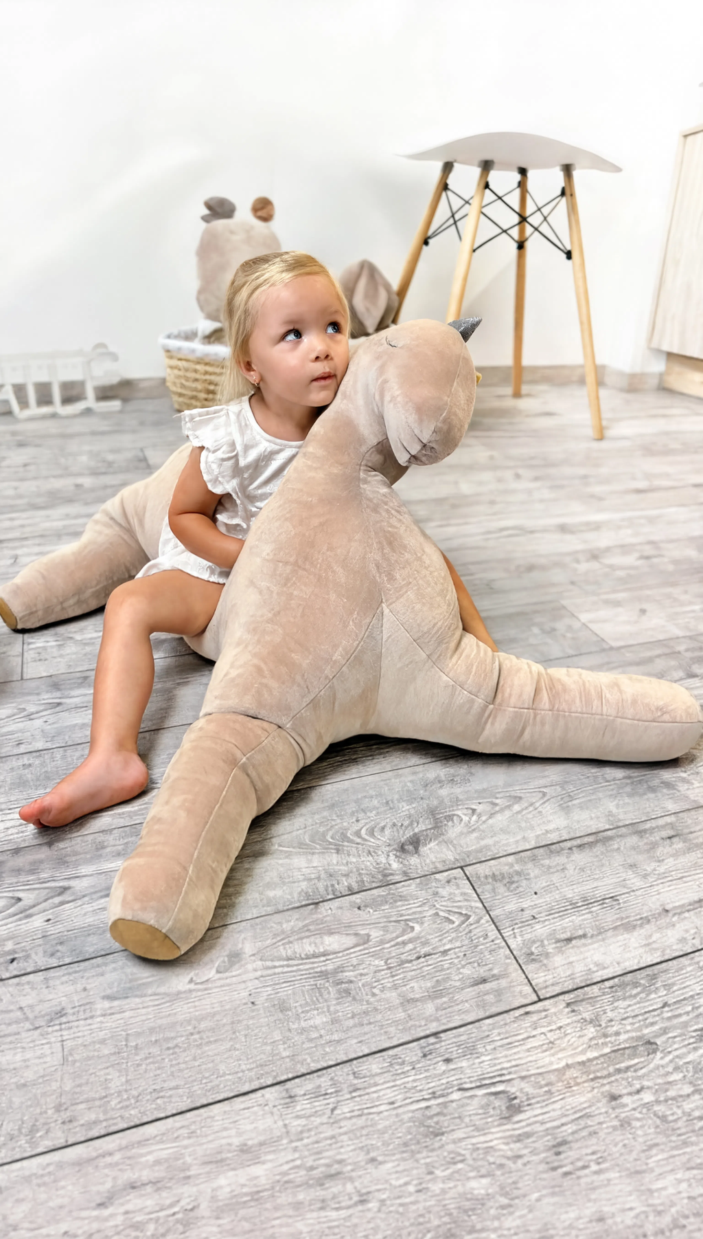 Child playing with a large stuffed animal on a wooden floor
