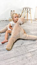 Child playing with a large stuffed animal on a wooden floor