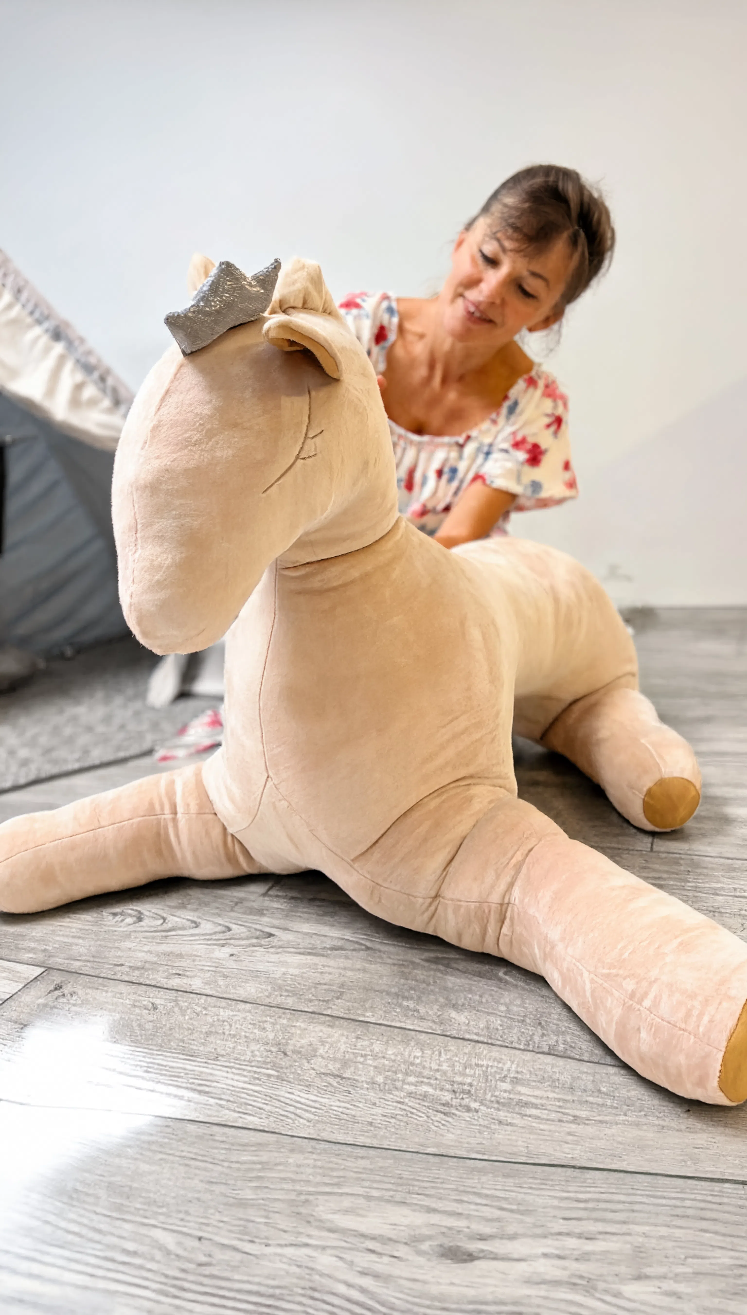 Woman playing with a large plush toy on a wooden floor
