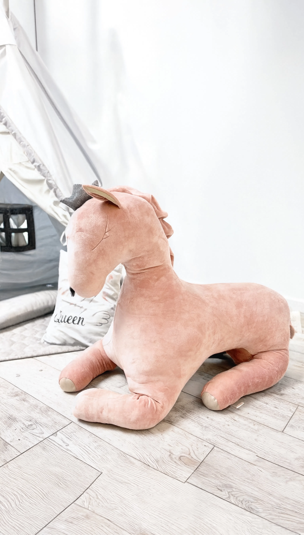 Plush dog-shaped pillow on a wooden floor with a blurred background