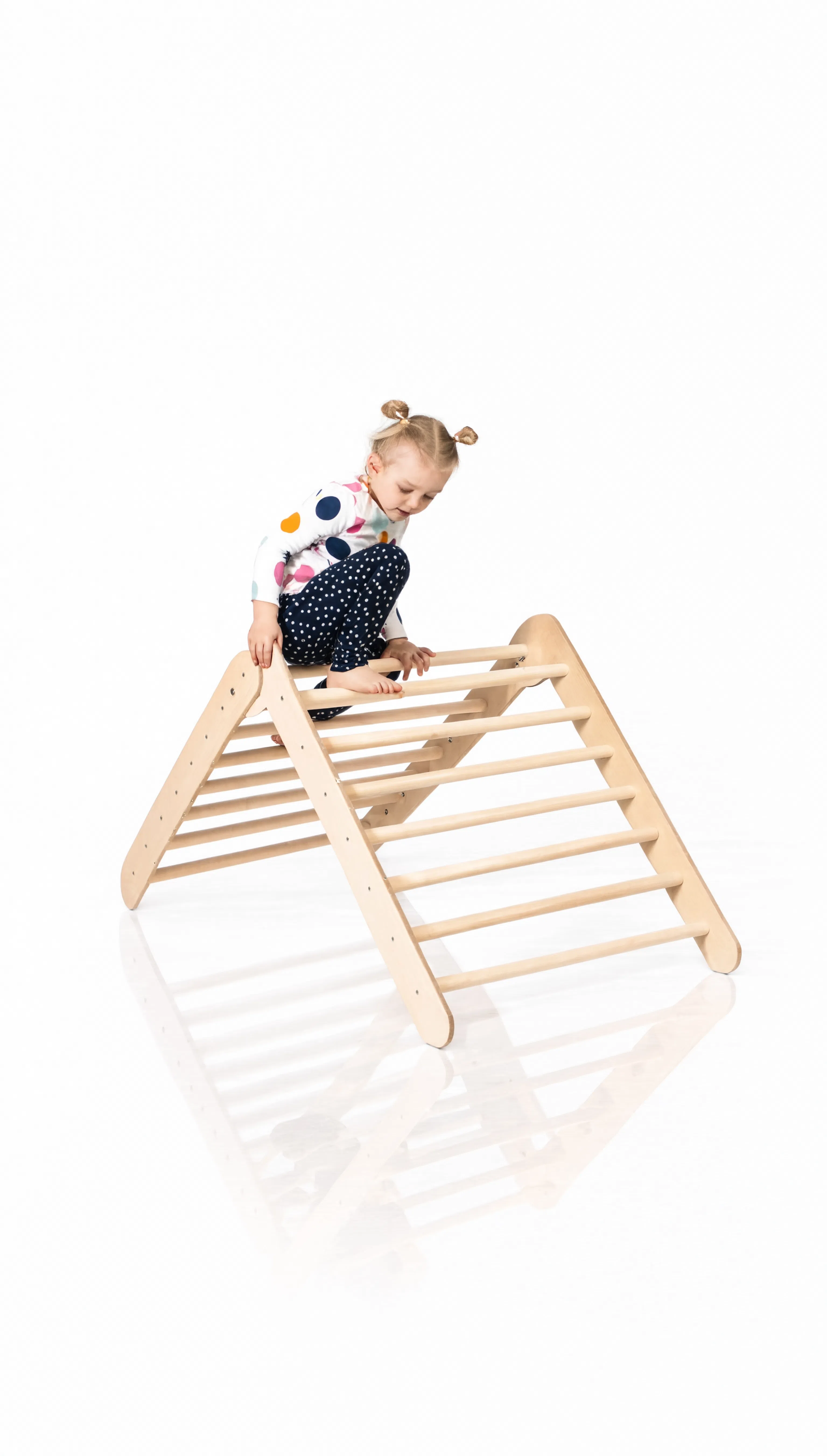 Child climbing a wooden triangle climber toy on a white background