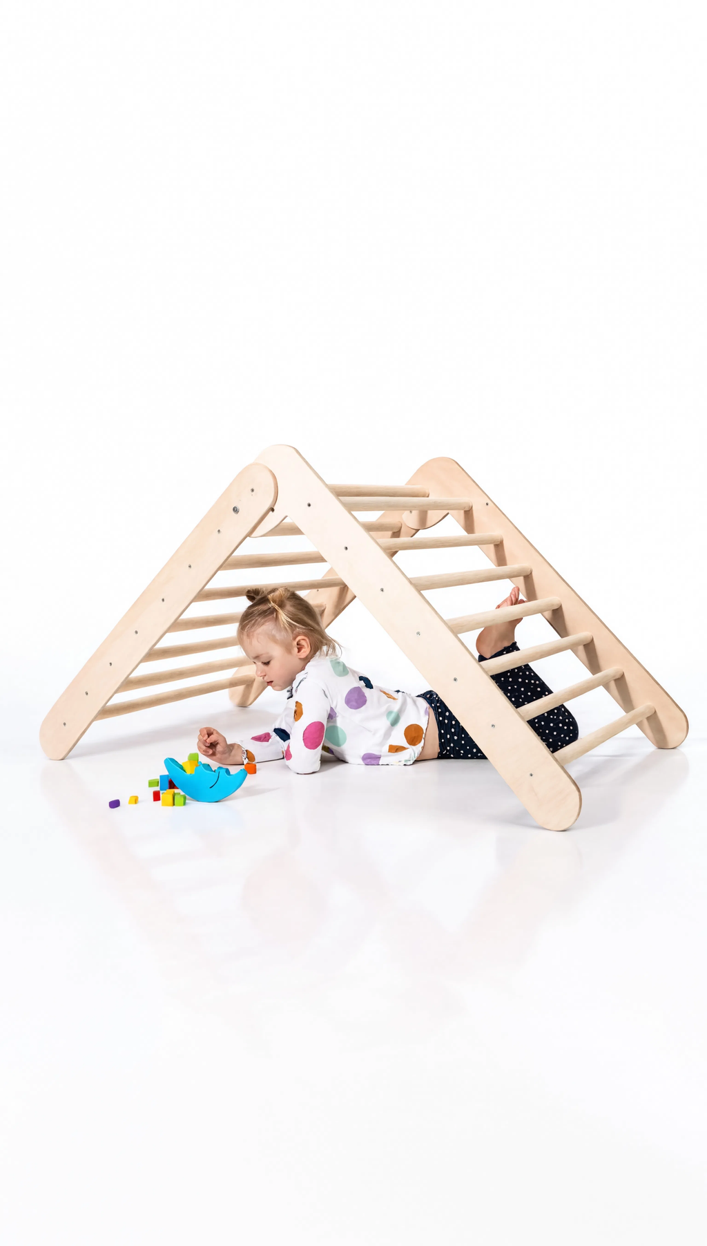 Child playing with a wooden climbing toy on a white background