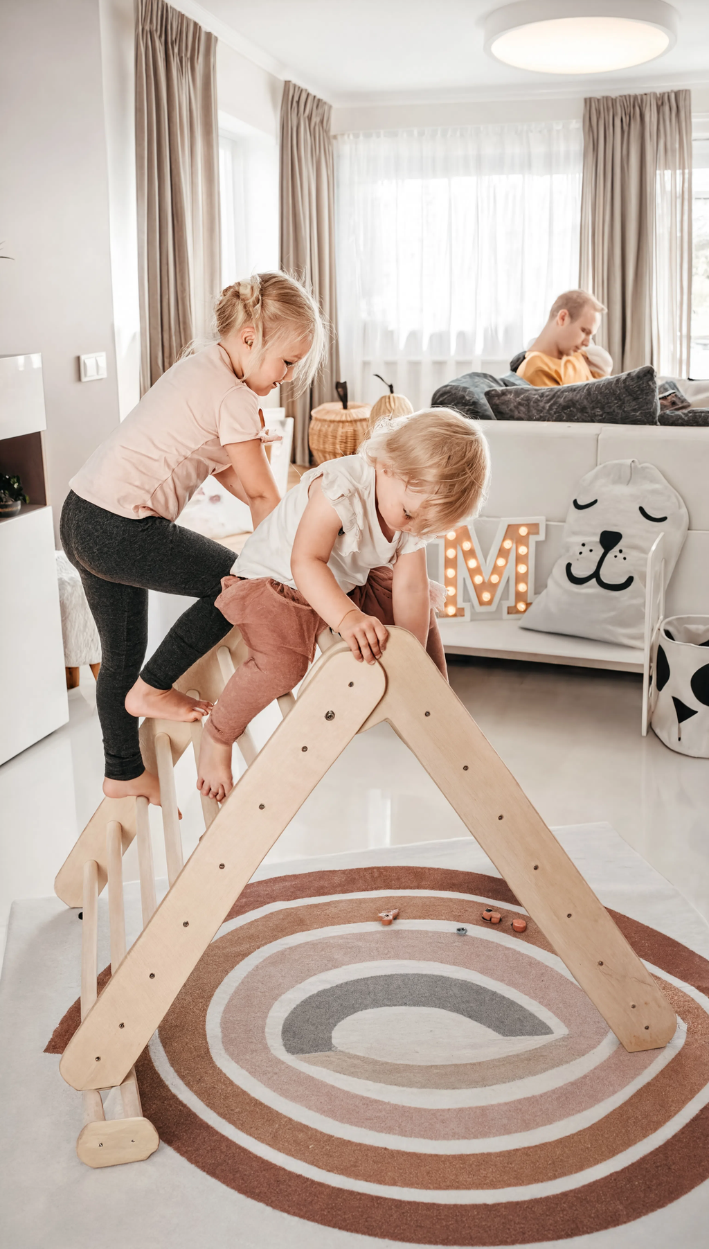 Children playing on a wooden climbing toy in a modern living room.