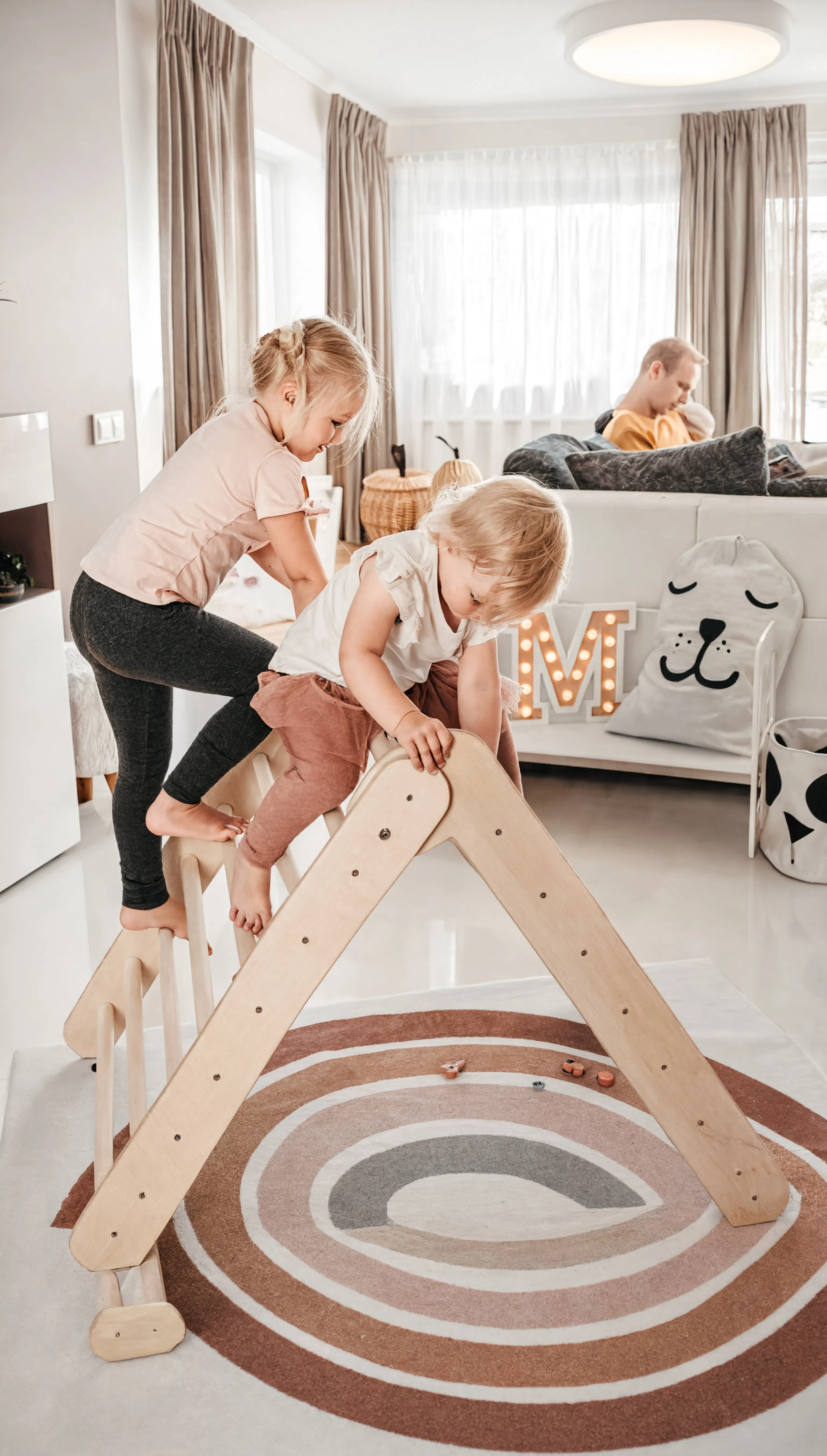 Children playing on a wooden climbing toy in a modern living room.