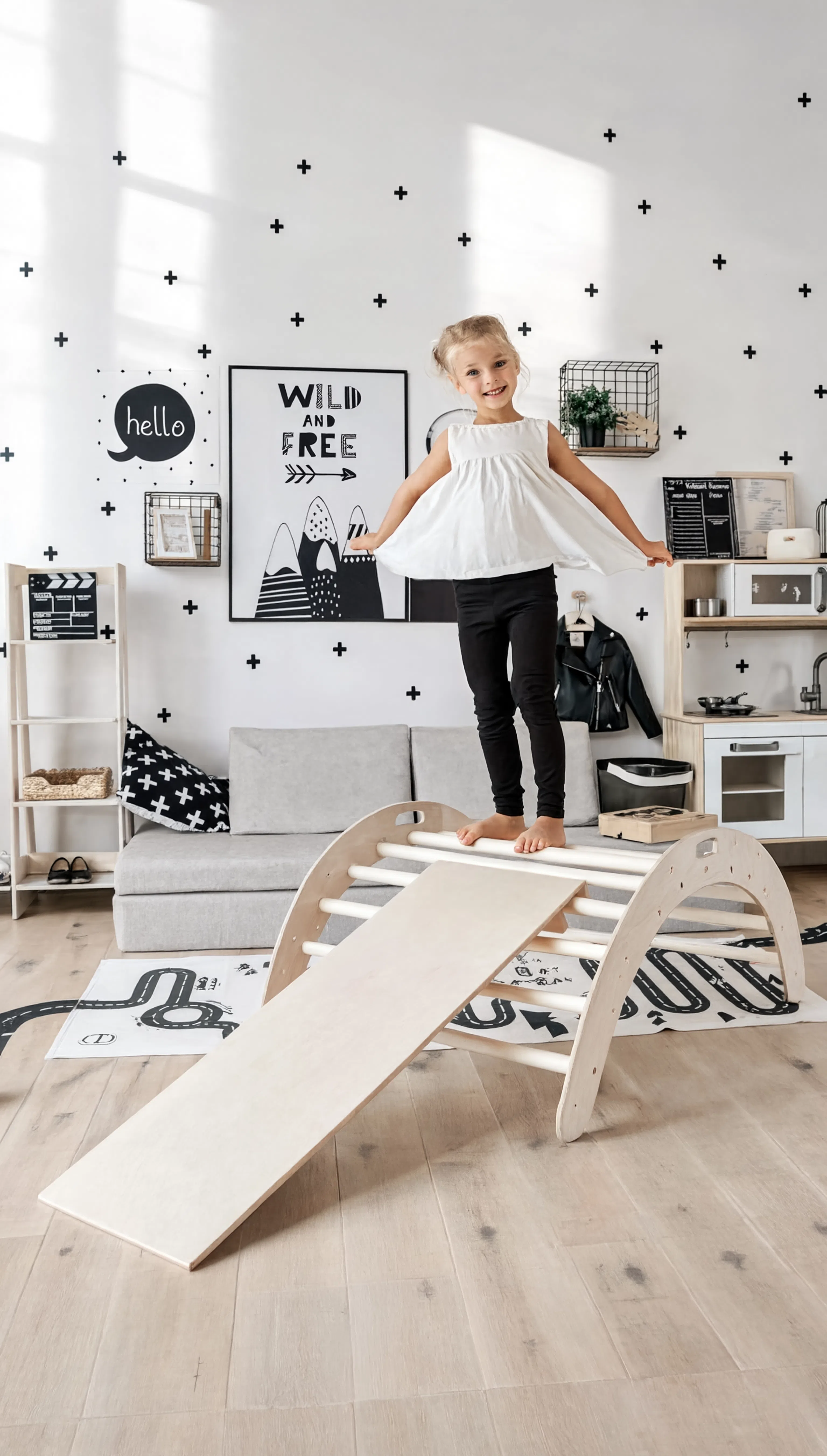 Child playing on a wooden seesaw in a room with decorative wall art and furniture.