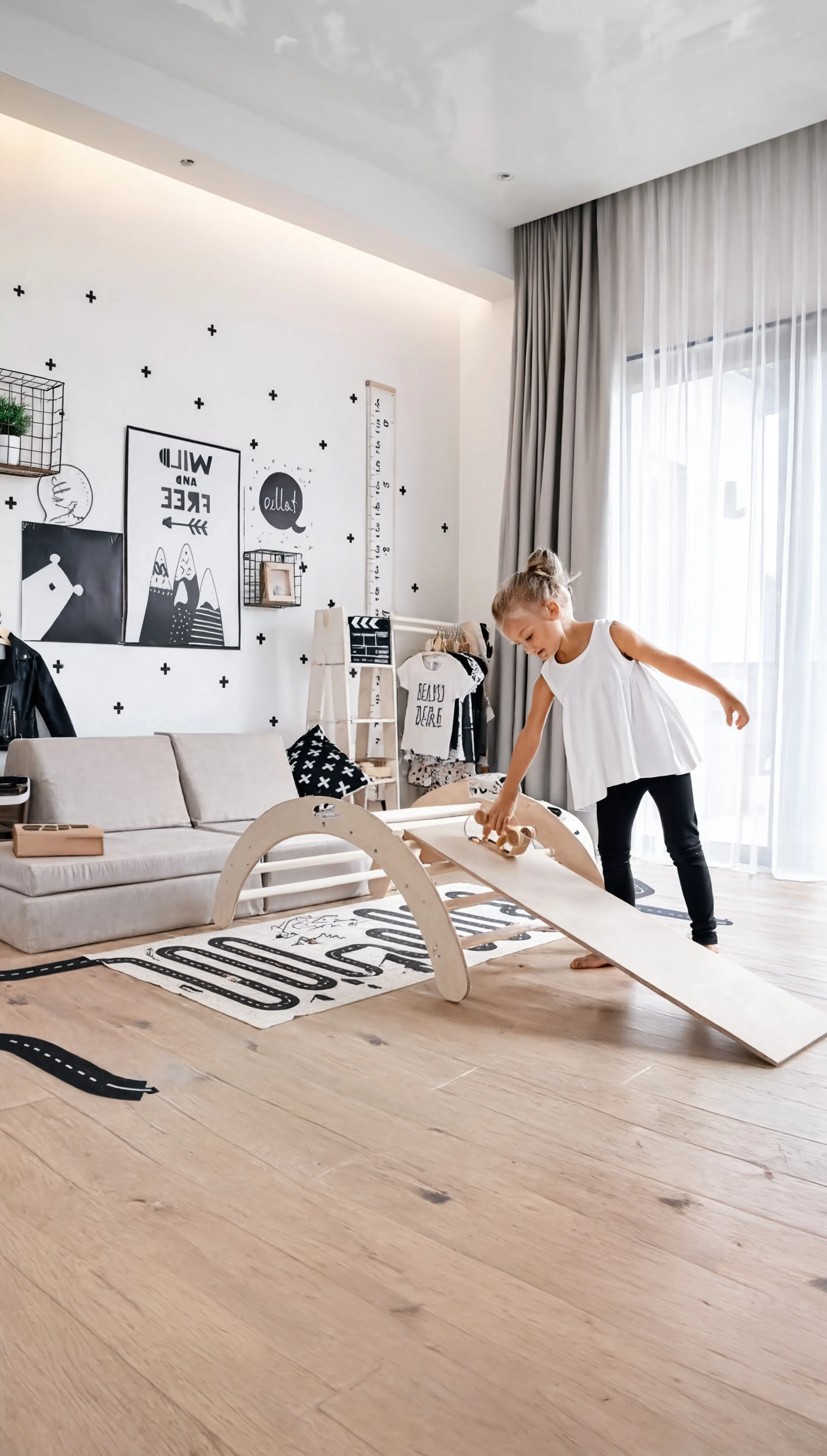 Child playing with a wooden balance beam in a modern living room.