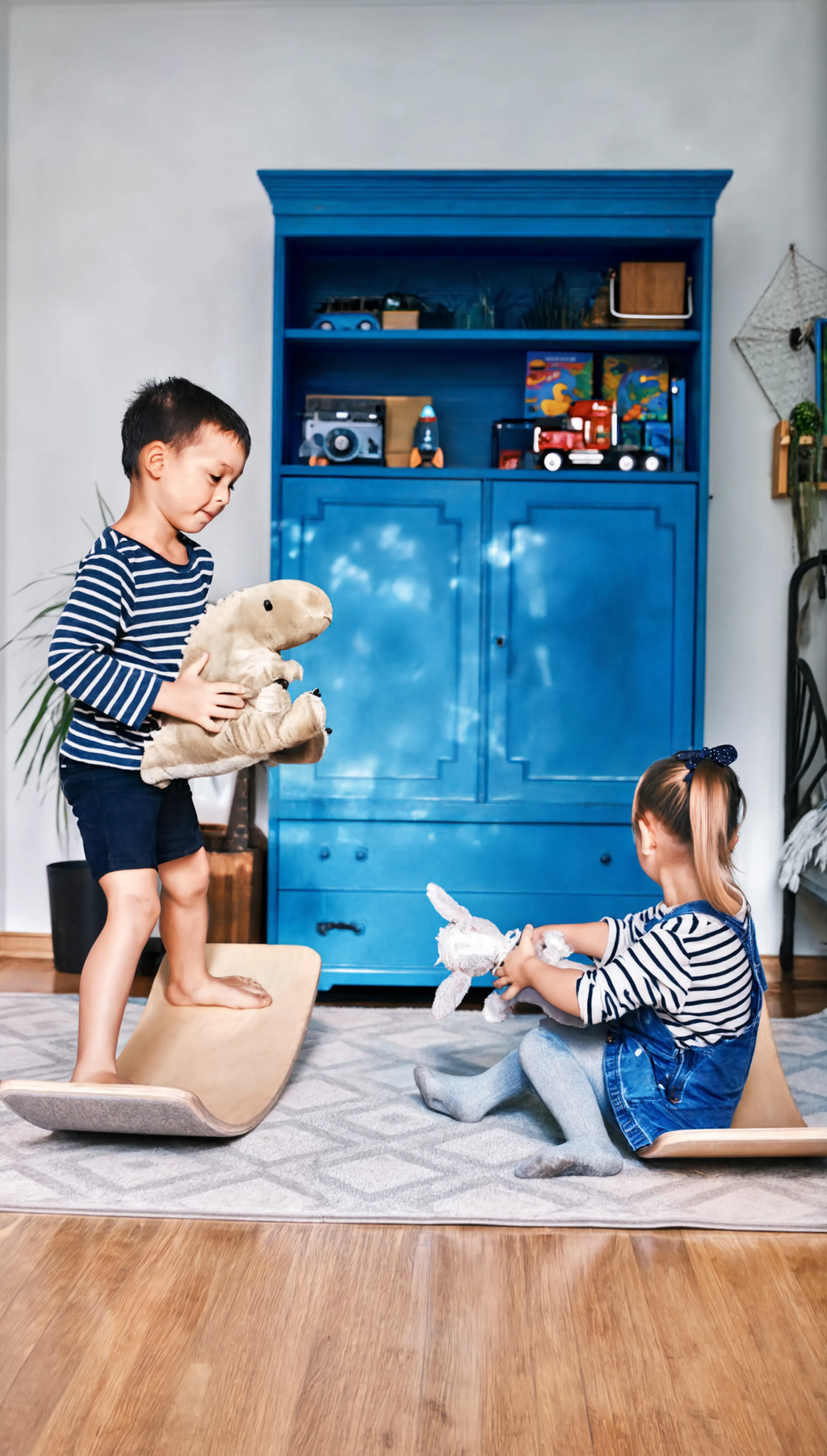 Two children playing with toys on a wooden floor in front of a blue cabinet.