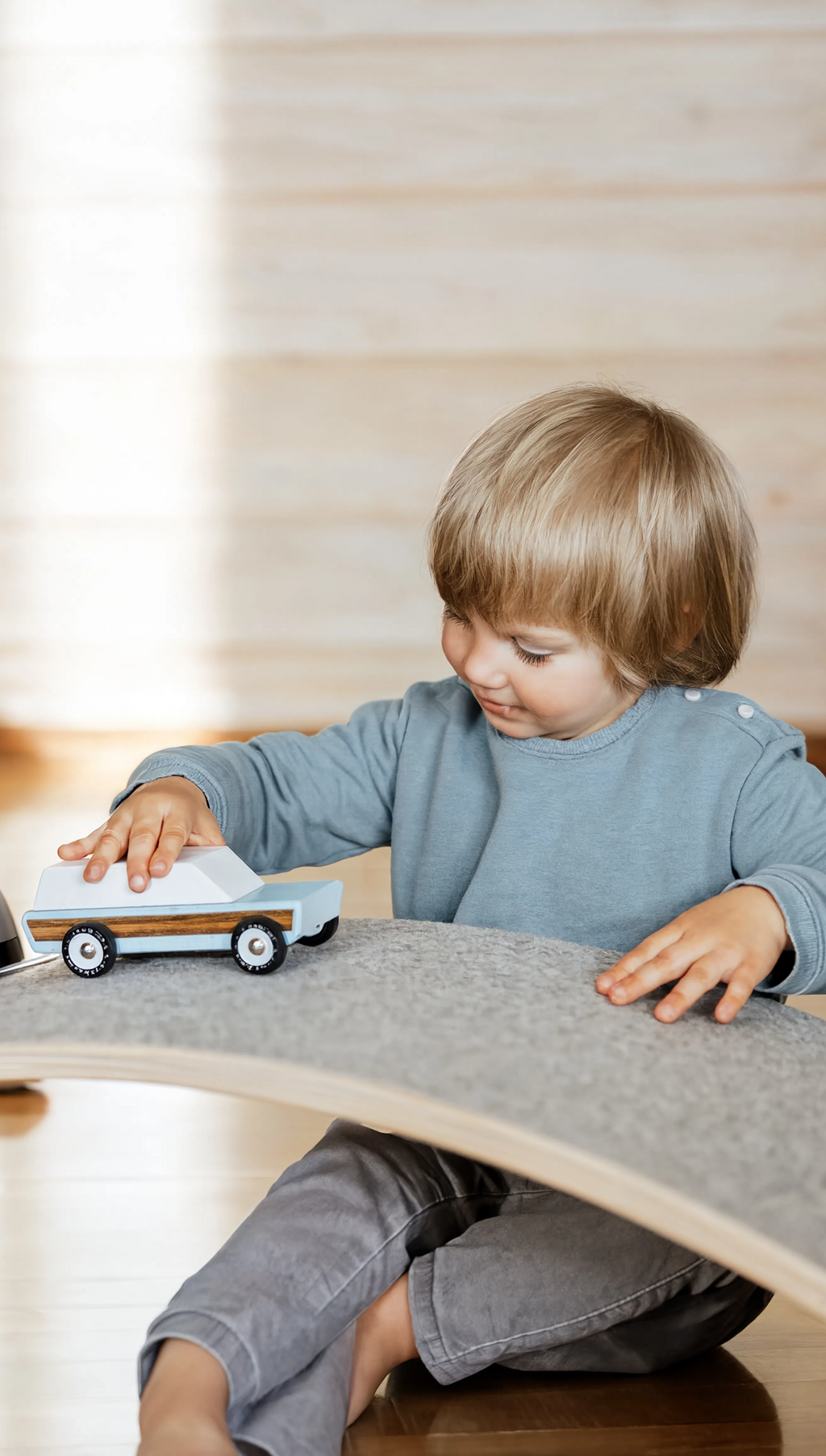 Child playing with toy cars on a wooden floor