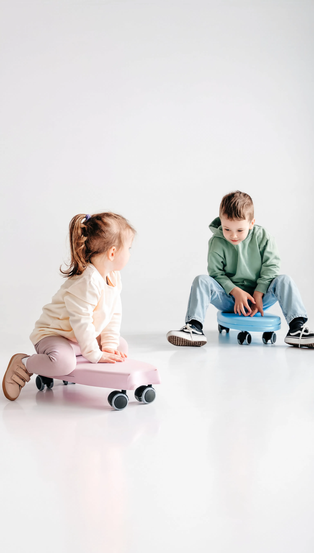 Two children playing with toy cars on a white floor.