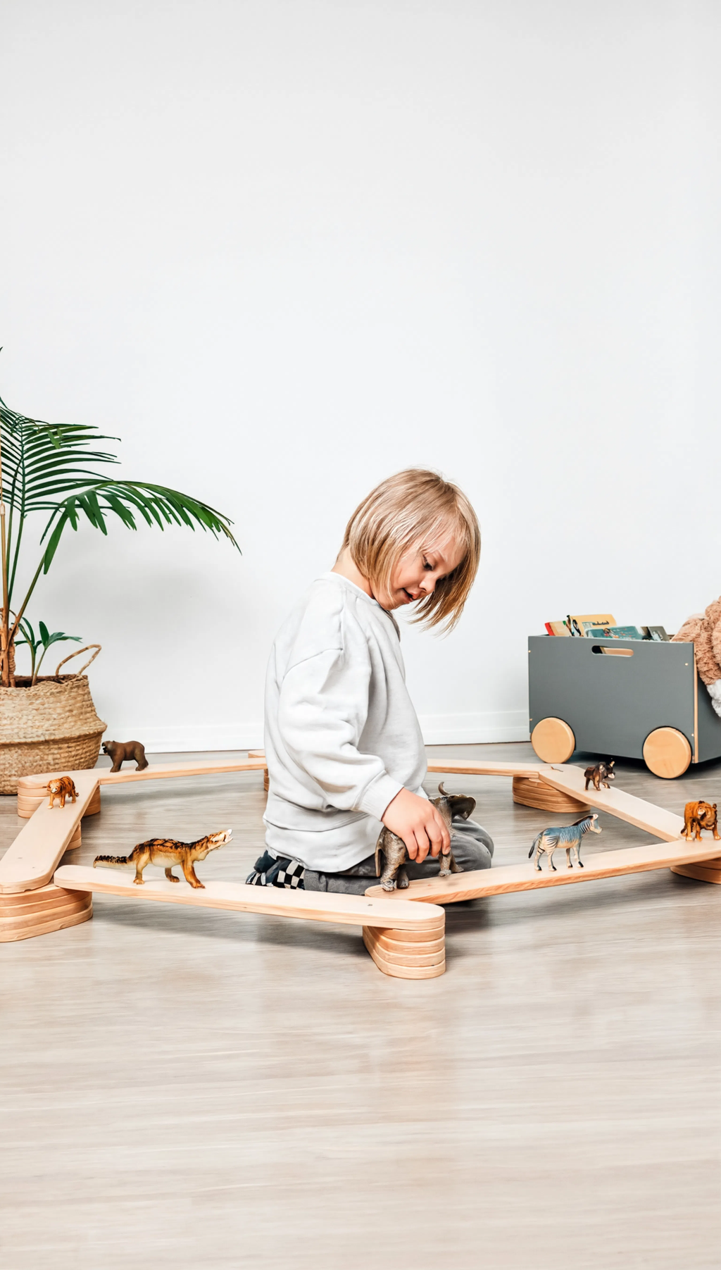 Child playing with wooden toys on a light wood floor.