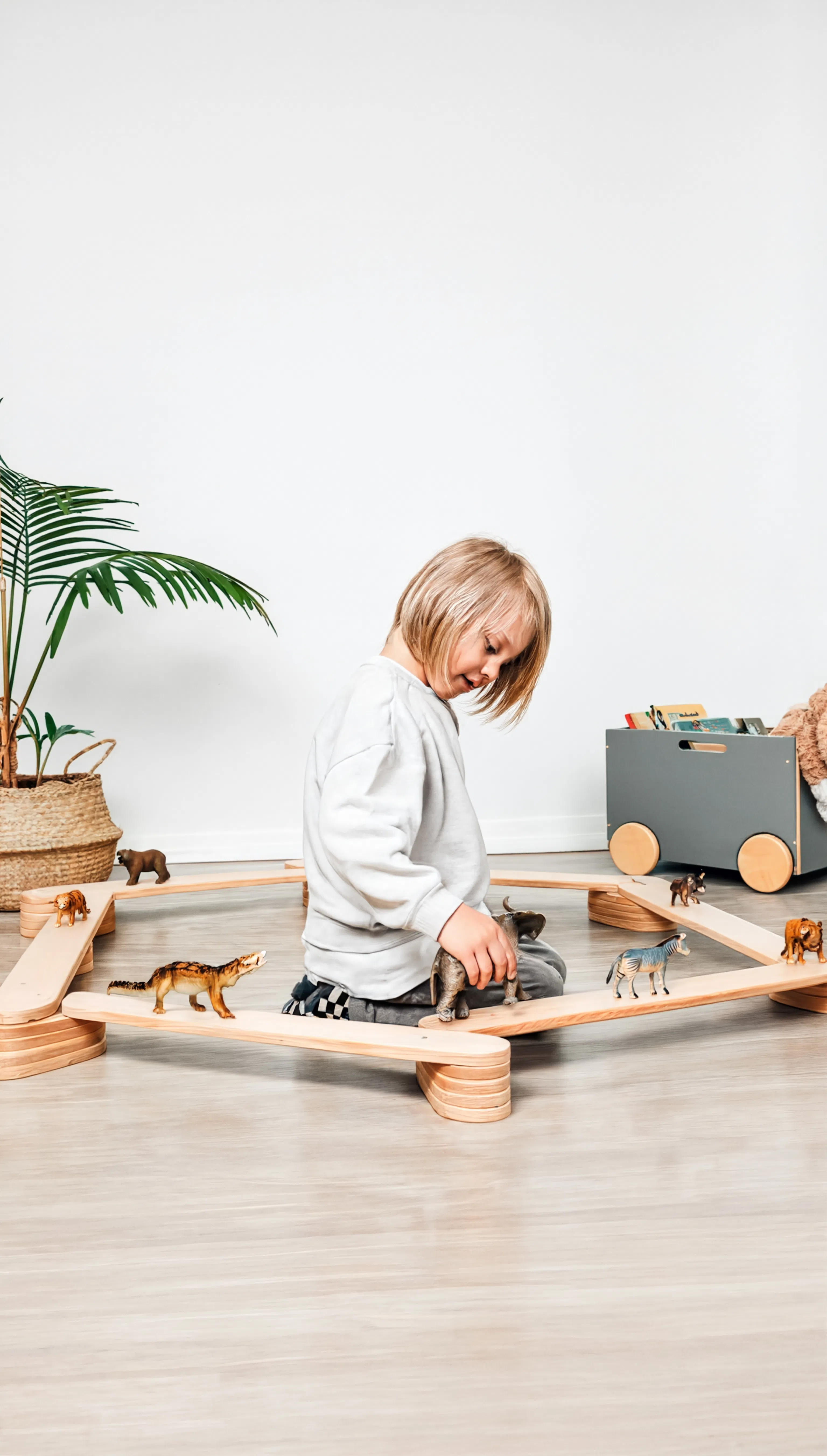 Child playing with wooden toys on a light wood floor.